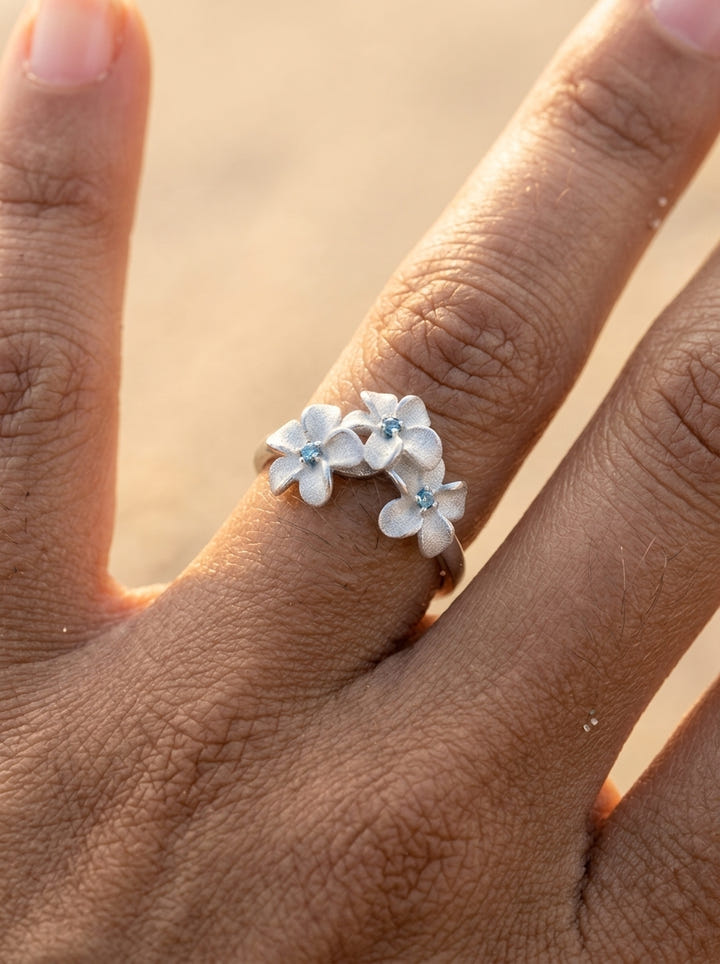 8mm 14k Plumeria Ring with 3 blue diamonds — studio macro closeup on model (brunette)