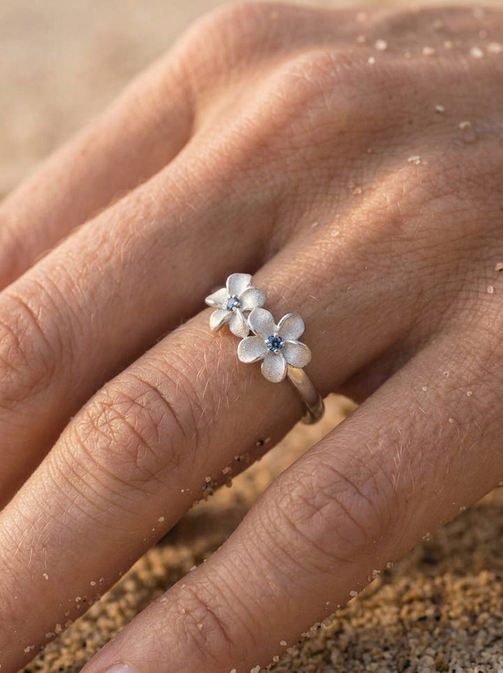 14k White Gold 8mm Plumeria Ring with 3 blue diamonds — close-up on model