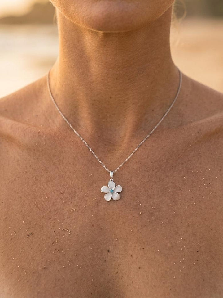 14k 15mm Plumeria Pendant with Blue Diamond — close-up on model