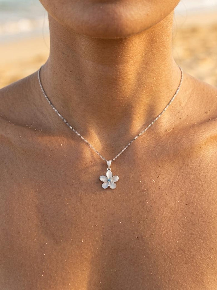 13mm 14k Plumeria Pendant with 0.03 carats blue diamond — close-up on model