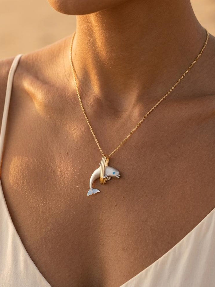 14k 2/tone 28mm "Jumping Loop" Dolphin Pendant with 2 blue diamonds — close-up on model