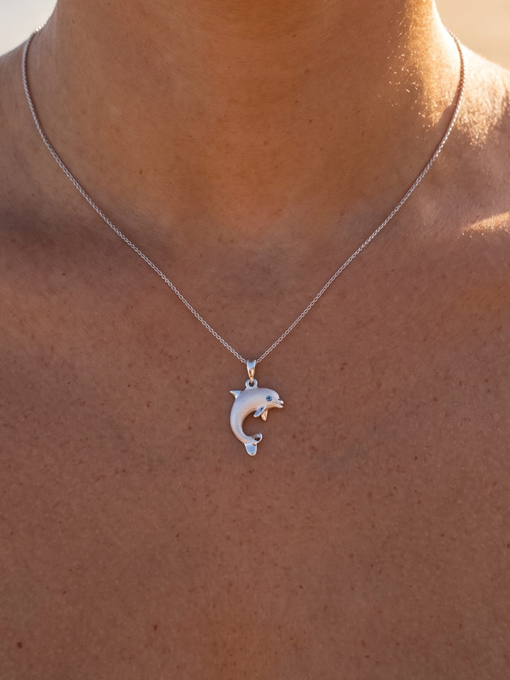 14k 15mm "Jumping Single" Dolphin Pendant with 0.01 carat blue diamond — close-up on model