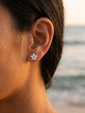 8mm 14k Plumeria Earring with 2 blue diamonds — close-up on model