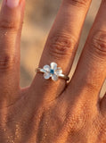 14k 10mm Plumeria Ring with blue diamond — close-up on model