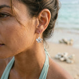 14k 11mm Plumeria Earrings with 2 blue diamonds — worn on model (brunette, view 3)