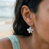 14k 11mm Plumeria Earrings with 2 blue diamonds — worn on model (brunette, view 4)