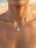 13mm 14k Plumeria Pendant with 0.03 carats blue diamond — close-up on model