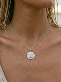 14k 21mm Sand Dollar Pendant with 12 diamonds — close-up on model