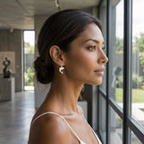 14k 15mm "Jumping Single" Dolphin Ball Post Earrings with 2 blue diamonds — worn on model (brunette, view 1)